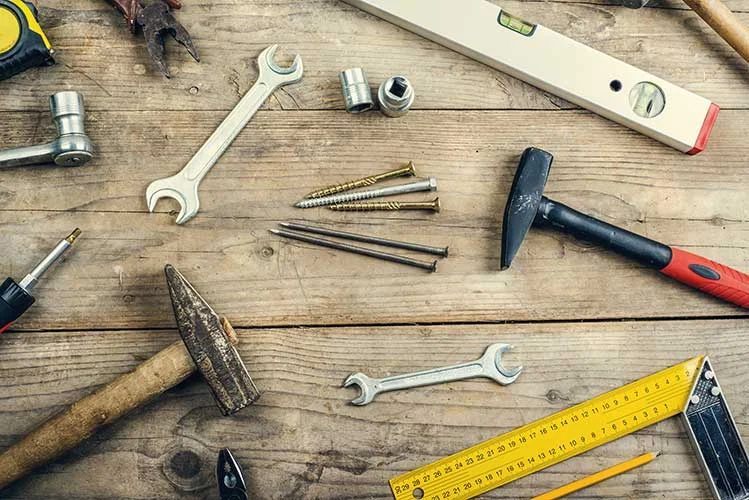 desk-of-a-carpenter-with-different-tools-studio-shot-on-a-wooden-background-SBI-305132275