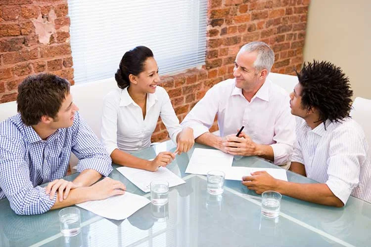 four-businesspeople-in-boardroom-smiling-SBI-301026951